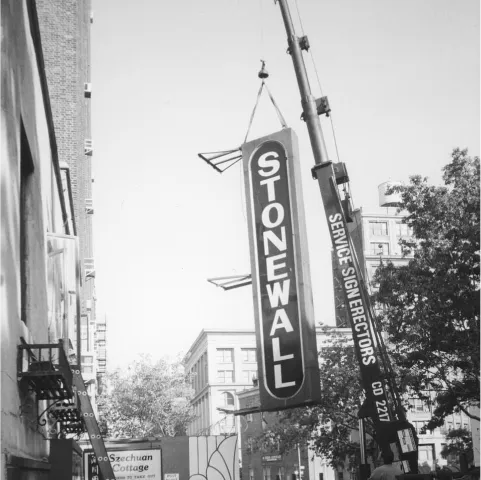 The stonewall inn sign being lifted by a crane.